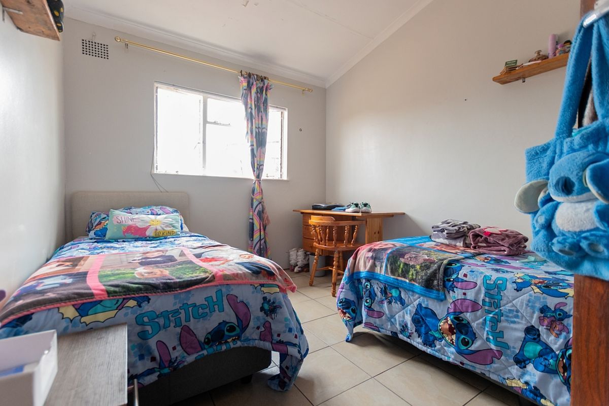 A functional bedroom featuring tiled flooring, a window for natural light, and built-in shelving, offering a practical space for rest or study.
