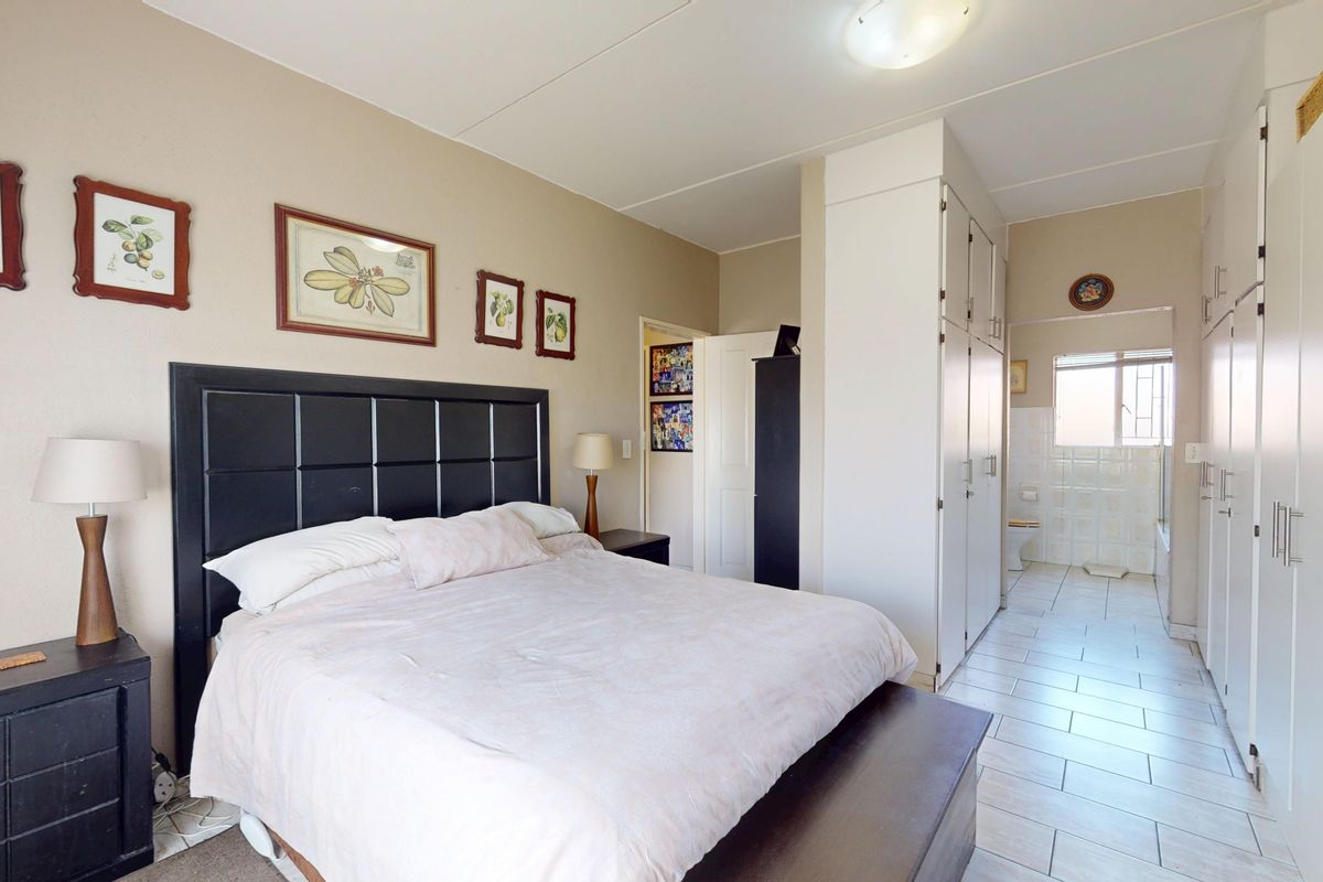 Spacious bedroom featuring extensive built-in cupboards, tiled flooring, and direct access to an en-suite bathroom.