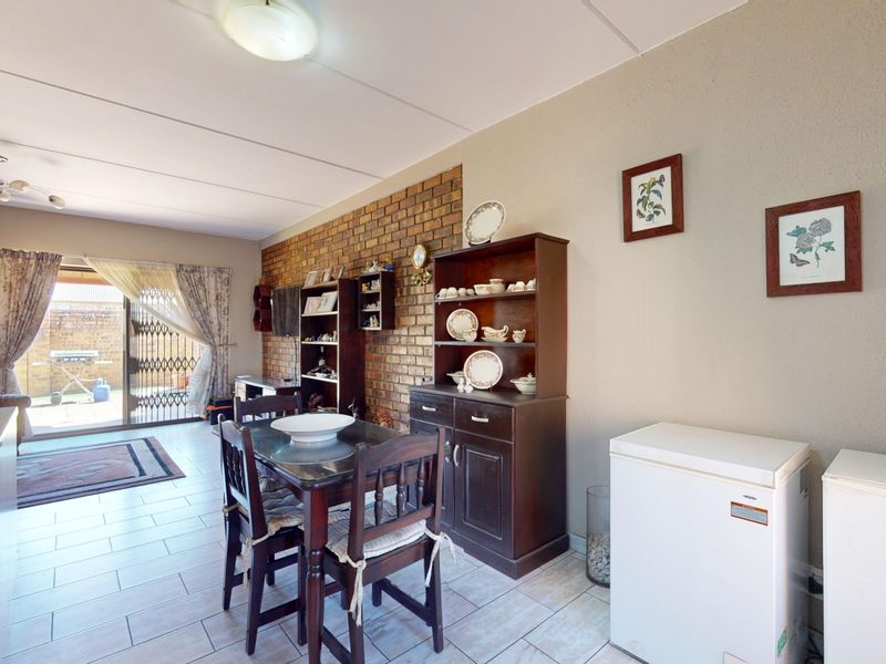 Open plan living and dining area featuring an exposed brick wall, tiled flooring, and sliding door access to the rear patio.