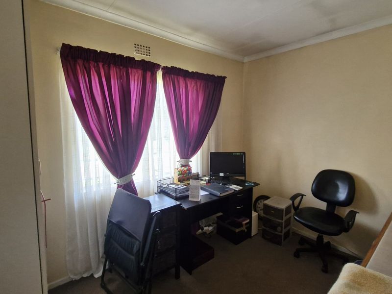 A functional bedroom featuring a built-in cupboard and natural light through a window, suitable for use as a bedroom or home office space.