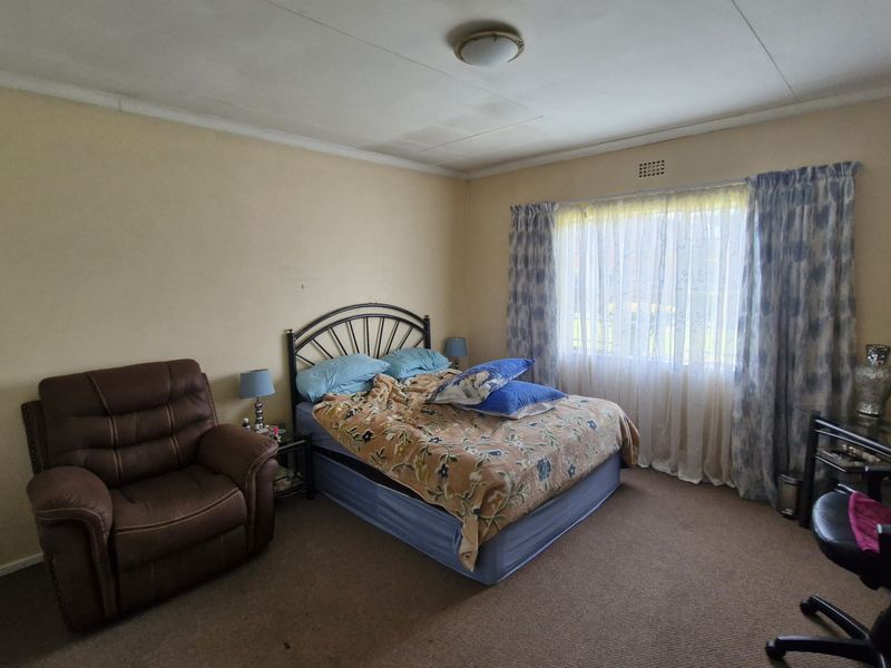 A bedroom featuring carpeted flooring, a built-in cupboard, and a ceiling-mounted light fixture, requiring cosmetic updates to improve its overall condition.