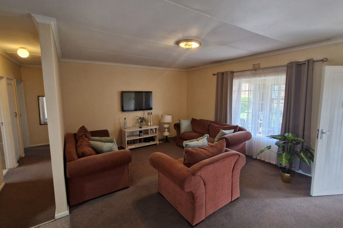 A spacious living room featuring neutral walls, carpeted flooring, and direct access to an outdoor patio area through a glass door.