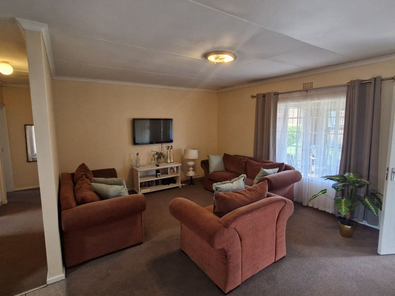 A spacious living room featuring neutral walls, carpeted flooring, and direct access to an outdoor patio area through a glass door.