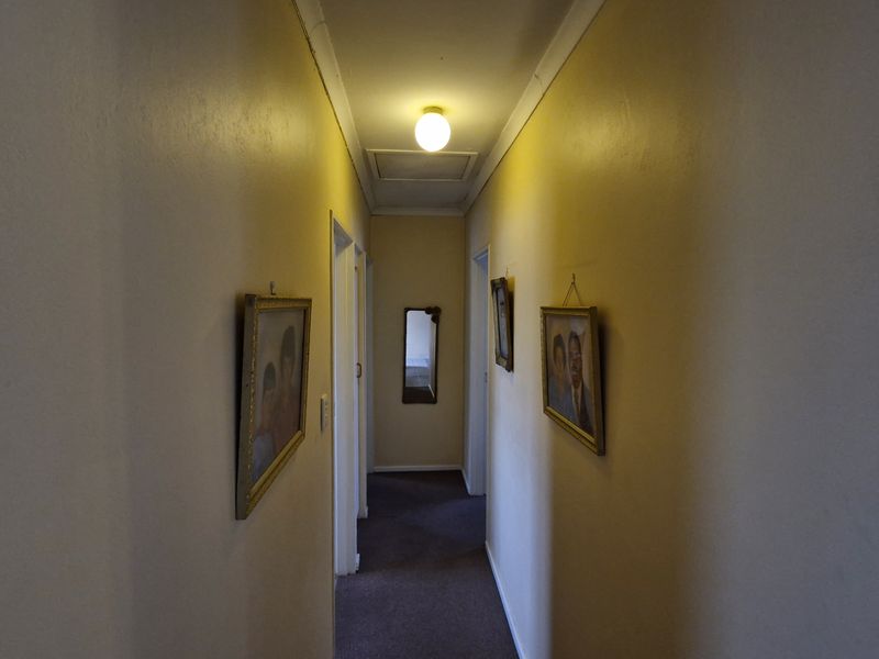 A functional residential hallway featuring neutral walls, carpeted flooring, and a ceiling access hatch.