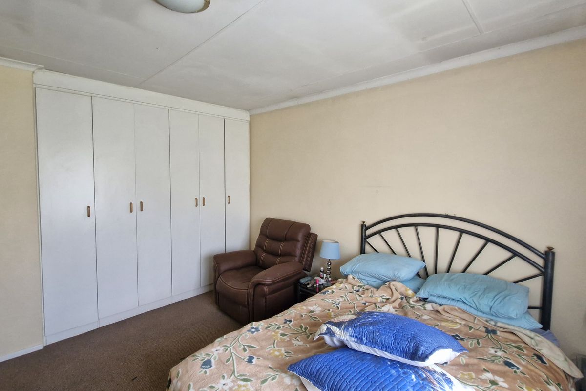 A bedroom featuring built-in cupboards, carpeted flooring, and a standard ceiling finish, offering a functional space ready for cosmetic updates.