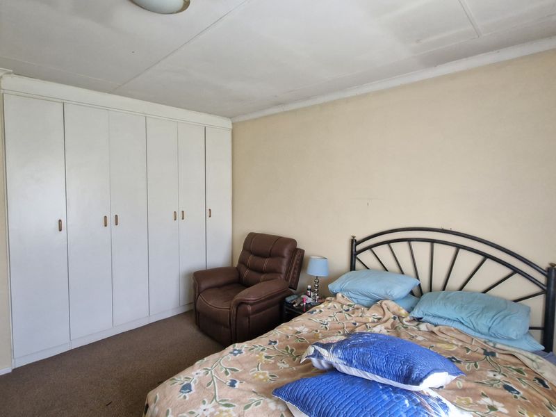 A bedroom featuring built-in cupboards, carpeted flooring, and a standard ceiling finish, offering a functional space ready for cosmetic updates.