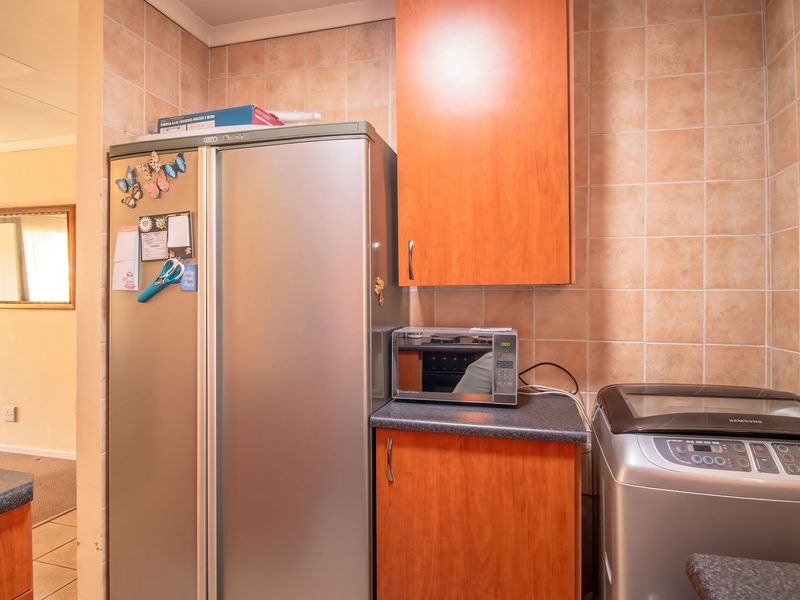 A functional laundry area featuring built-in wooden cabinetry, tiled splashbacks, and durable laminate countertops, providing practical storage and workspace for household utility tasks.