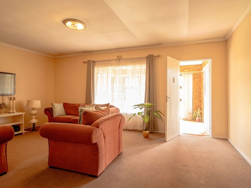 A comfortable living room featuring neutral wall tones, carpeted flooring, and direct access to an outdoor patio area.