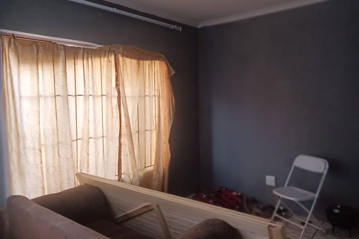 A simple bedroom featuring tiled flooring and dark painted walls, offering a blank canvas for personalization.