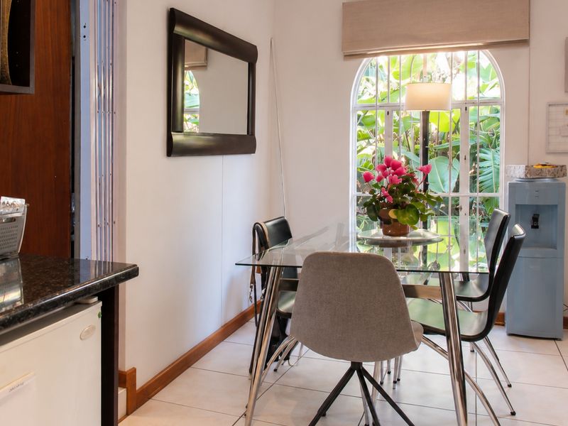 Open plan dining area featuring tiled flooring, a distinctive arched window with security bars, and a compact kitchen workspace with granite countertops.