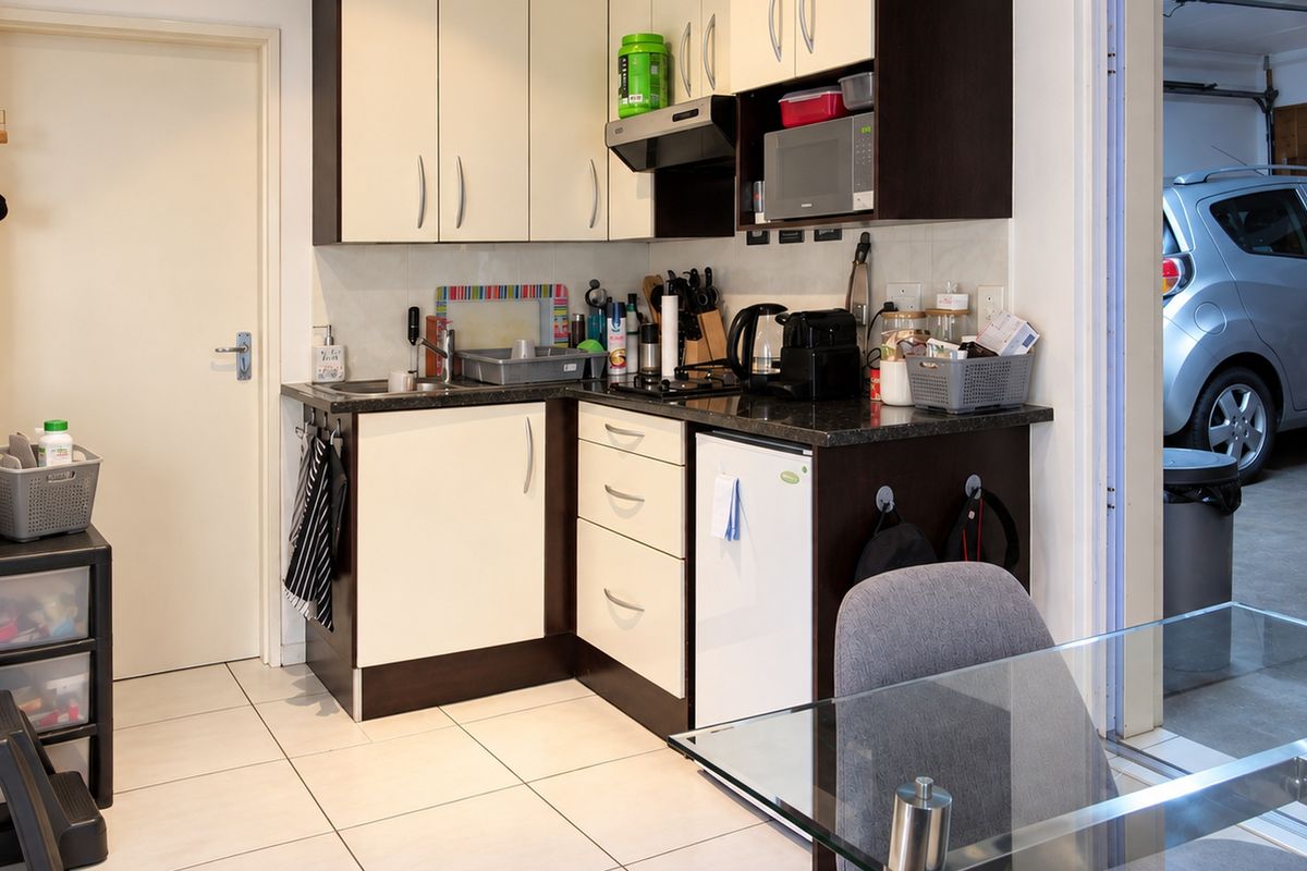 Compact kitchen area featuring built-in cabinetry, laminate countertops, and tiled flooring, providing a functional prep space with integrated appliances.