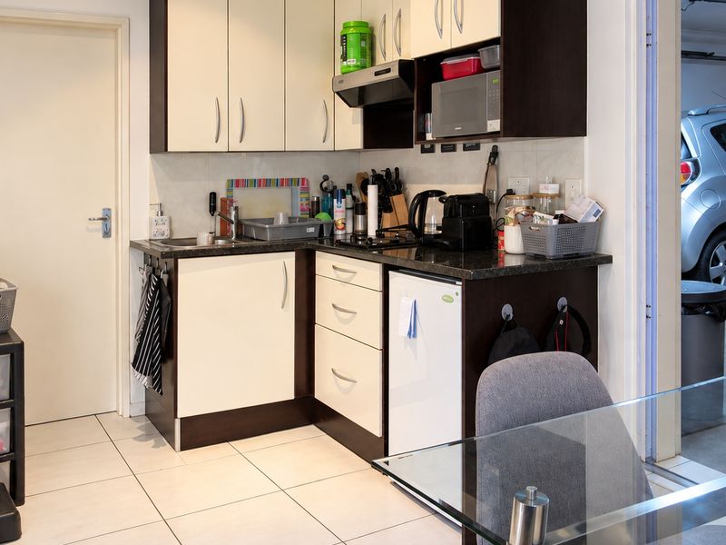 Compact kitchen area featuring built-in cabinetry, laminate countertops, and tiled flooring, providing a functional prep space with integrated appliances.