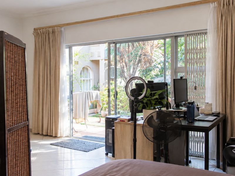 Bedroom featuring tiled flooring and large sliding glass doors providing direct access to the rear garden area.