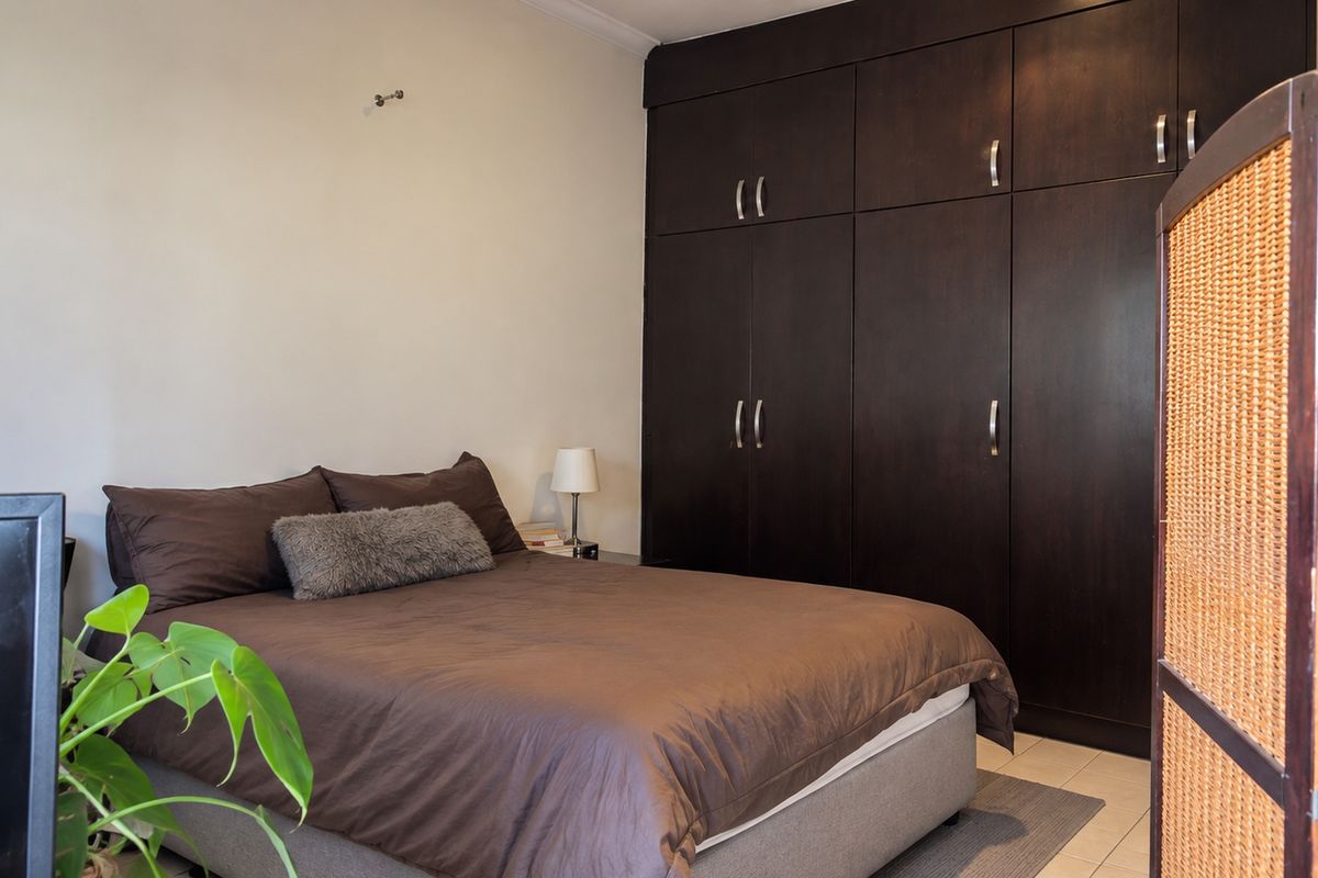 A bedroom featuring dark wood built-in cupboards and tiled flooring, offering ample storage space.