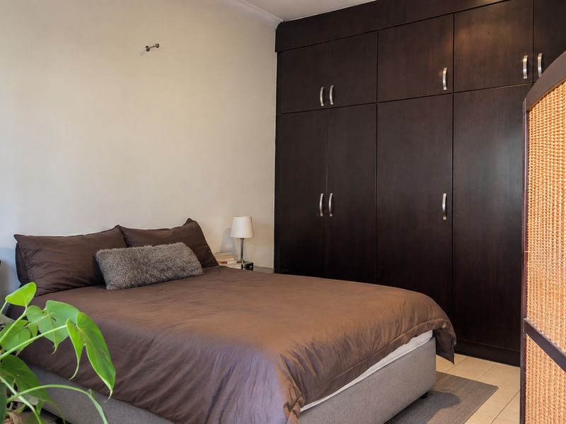 A bedroom featuring dark wood built-in cupboards and tiled flooring, offering ample storage space.