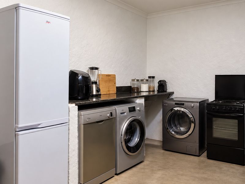 A functional laundry and utility area featuring concrete flooring, a granite countertop, and dedicated plumbing connections for appliances.