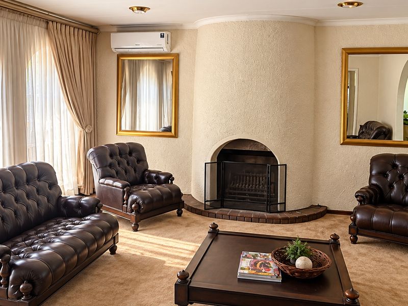 A comfortable living room featuring a prominent arched fireplace, textured walls, and a wall-mounted split-system air conditioner.