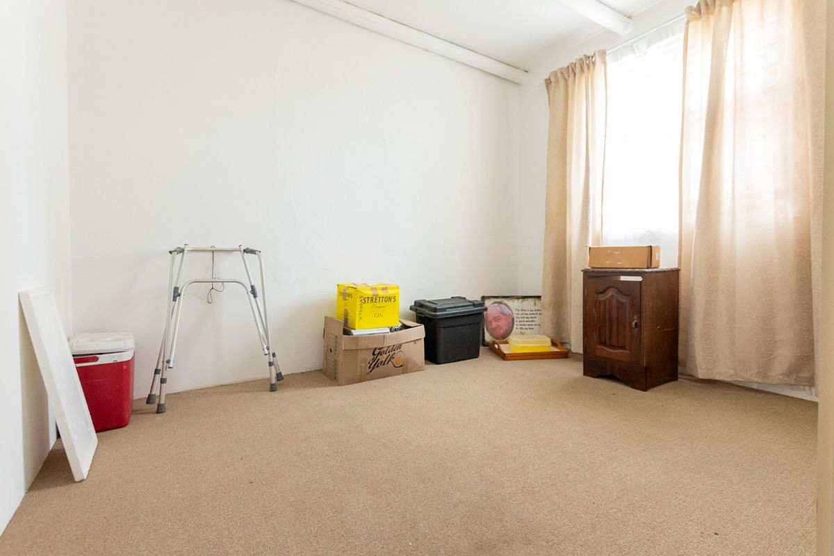 A vacant bedroom featuring neutral wall finishes and carpet flooring, offering a blank canvas for potential interior design and renovation.