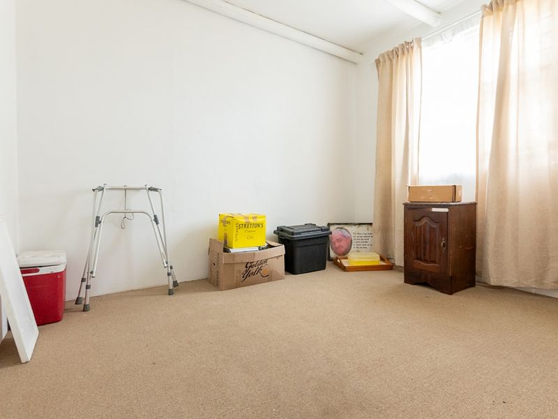 A vacant bedroom featuring neutral wall finishes and carpet flooring, offering a blank canvas for potential interior design and renovation.
