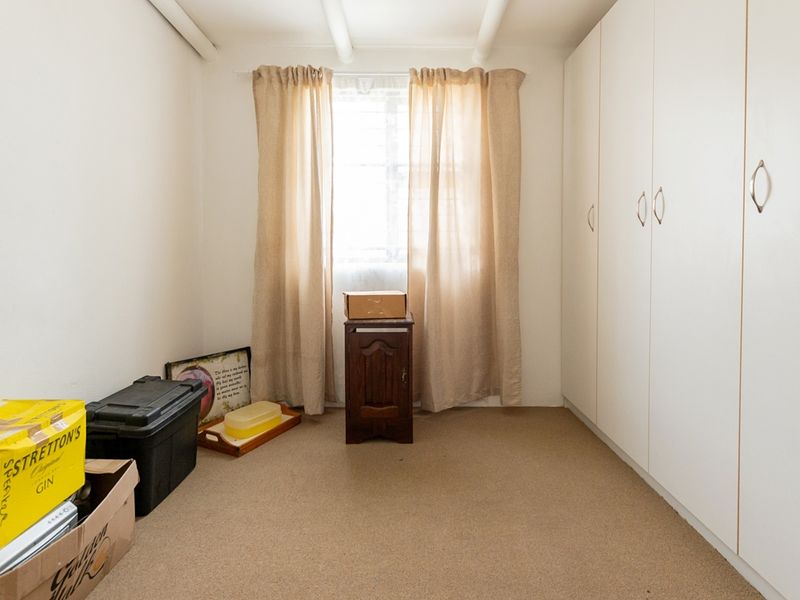 A simple bedroom featuring neutral carpeting and floor-to-ceiling built-in cupboards, offering a clean and functional space ready for personalization.