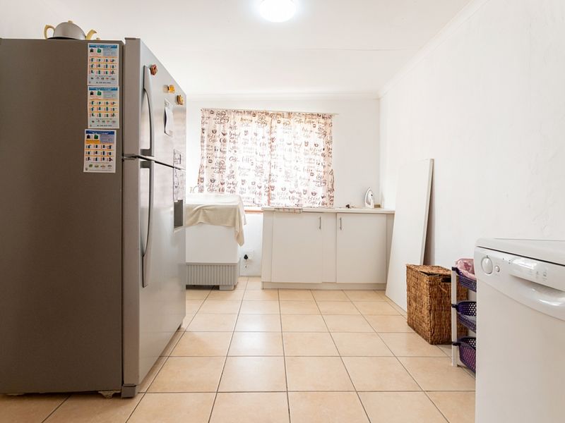 A functional laundry room featuring tiled flooring, built-in cabinetry, and a window, providing a practical space for household utility tasks.