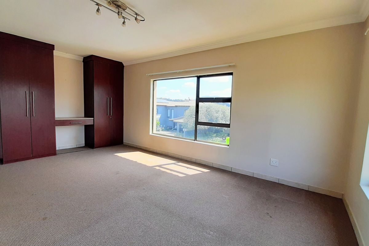 Spacious bedroom featuring built-in cupboards, an integrated desk, and large windows providing ample natural light.