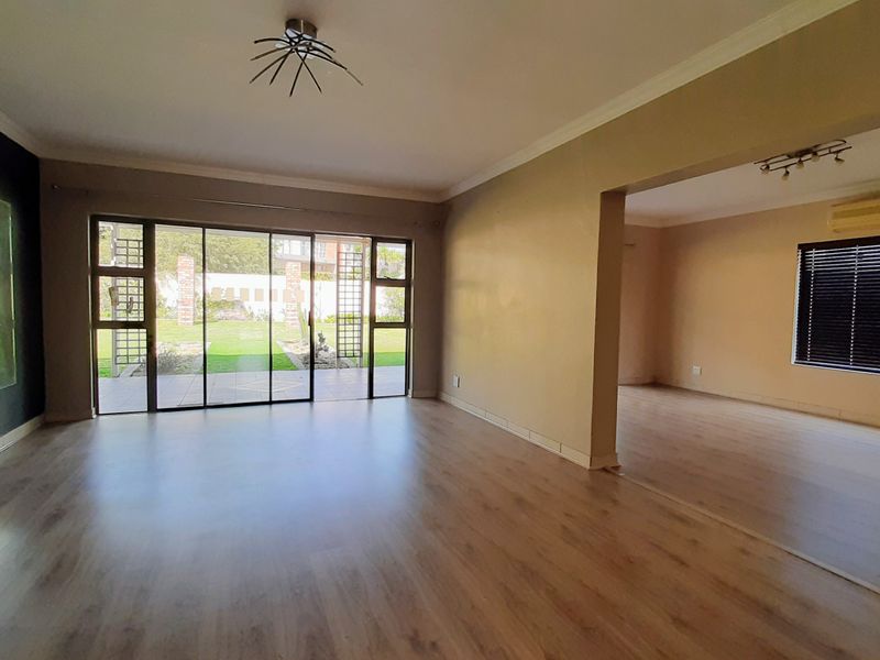 Spacious open-plan living area featuring laminate flooring, large sliding glass doors leading to the garden, and neutral wall tones.