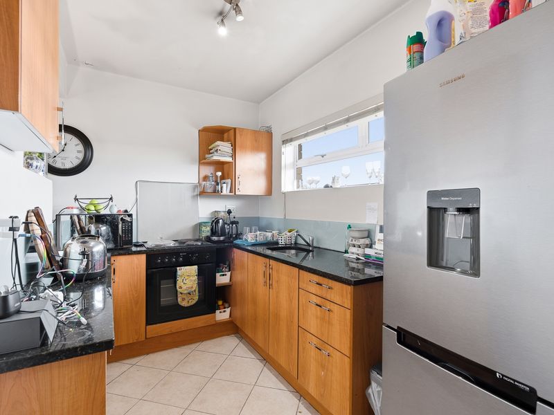 A functional kitchen featuring wooden cabinetry, granite countertops, a built-in oven, and tiled flooring, offering a practical layout for daily meal preparation.