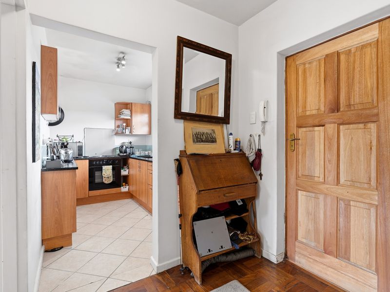 Entryway featuring a solid timber door and parquet flooring, providing direct access to an adjacent kitchen with built-in cabinetry and appliances.