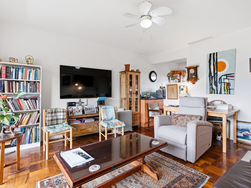 A comfortable living room featuring classic parquet flooring and a ceiling fan, offering a warm and inviting space for relaxation.