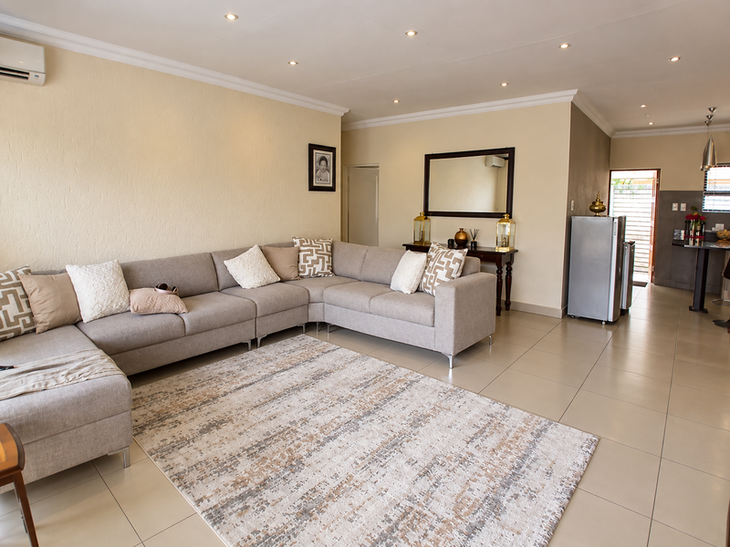 Spacious open-plan living area featuring neutral tiled flooring, recessed lighting, and a seamless transition to the kitchen space.
