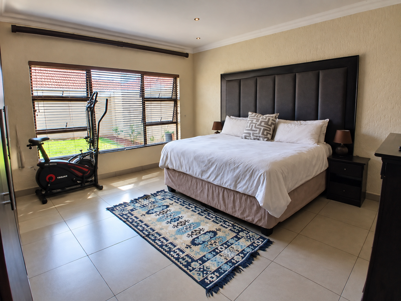 Spacious bedroom featuring tiled flooring, recessed downlighting, and large windows with fitted blinds, offering a bright and comfortable living space.