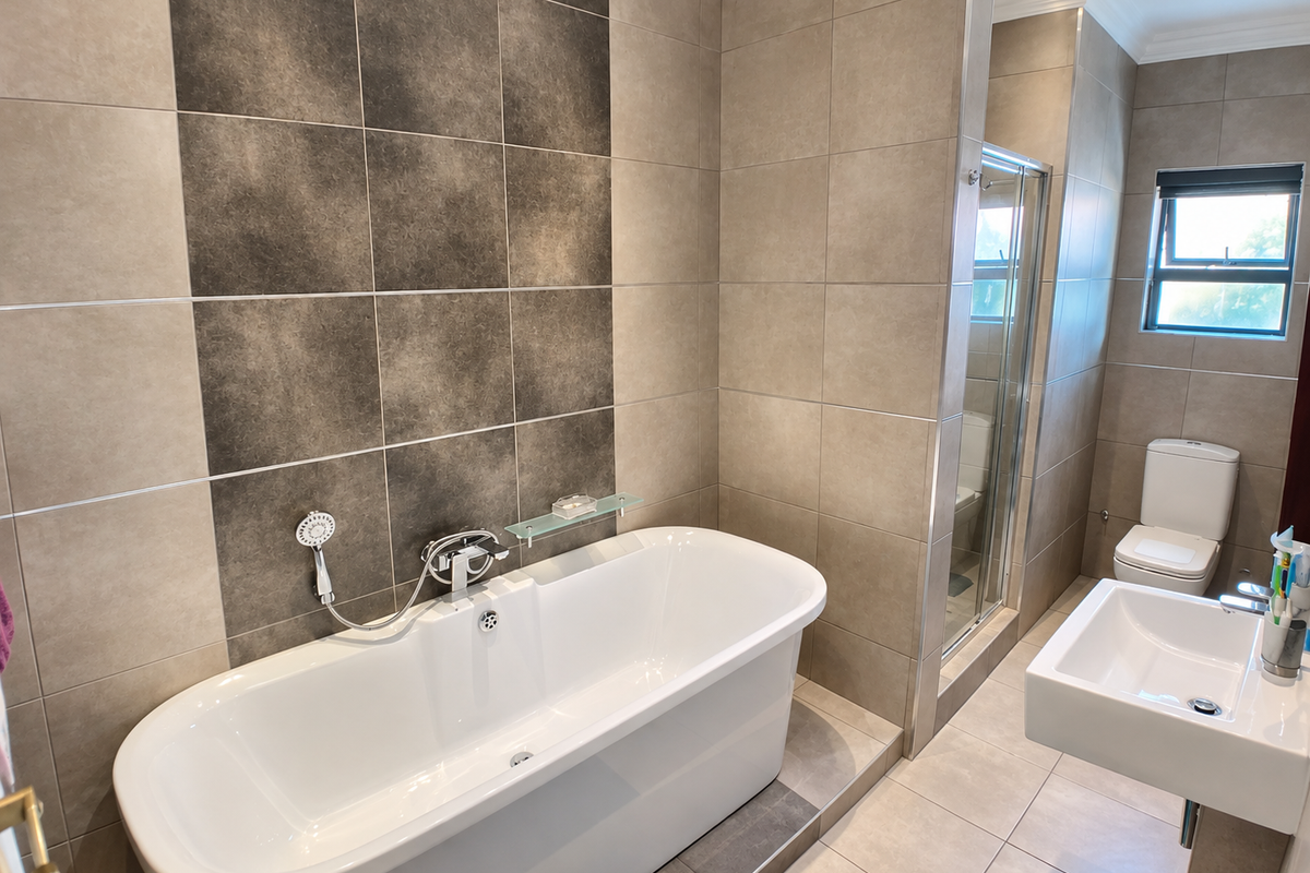Modern bathroom featuring a freestanding bathtub, glass-enclosed shower, wall-hung toilet, and contemporary basin with neutral-toned ceramic tiling throughout.