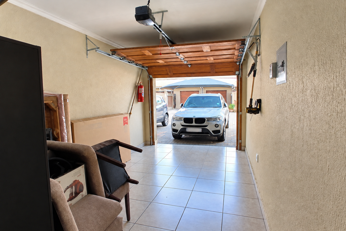 A clean, tiled garage featuring an automated door system, wall-mounted fire extinguisher, and an accessible electrical distribution board.
