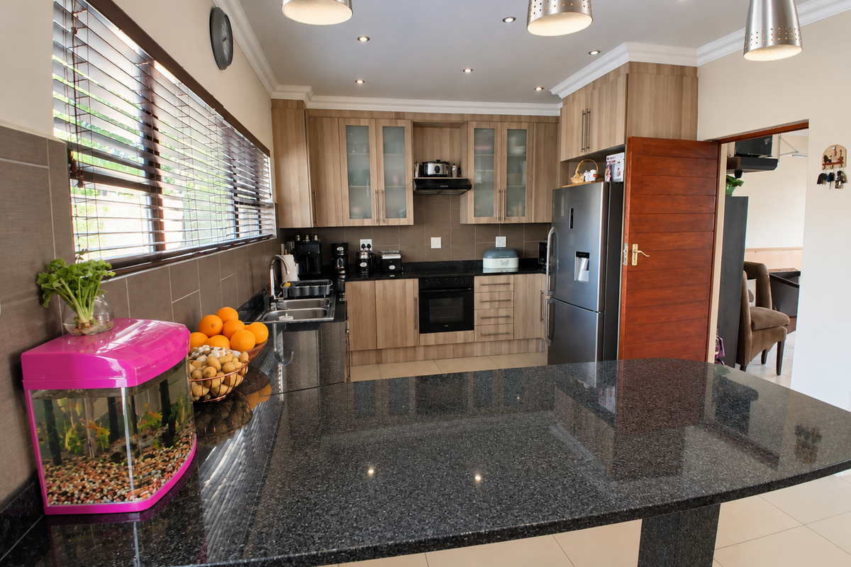 Modern kitchen featuring granite countertops, wooden cabinetry, built-in oven, hob, extractor fan, and tiled flooring with ample workspace and recessed lighting.