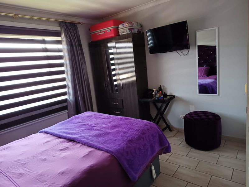 A functional bedroom featuring tiled flooring and window blinds, providing a comfortable and practical living space.