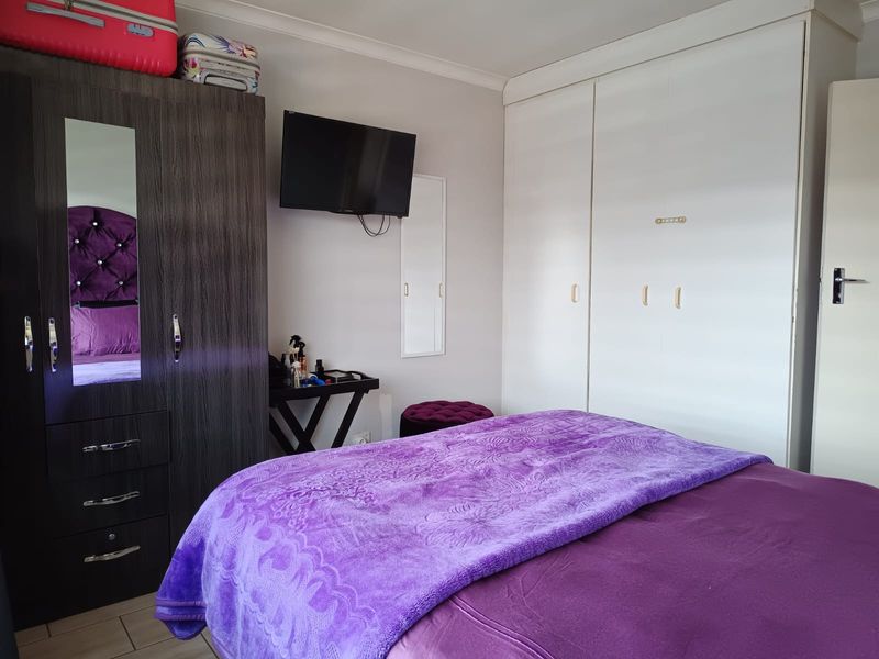 A bedroom featuring built-in cupboards, tiled flooring, and decorative coving, providing functional storage and a neutral base for interior design.