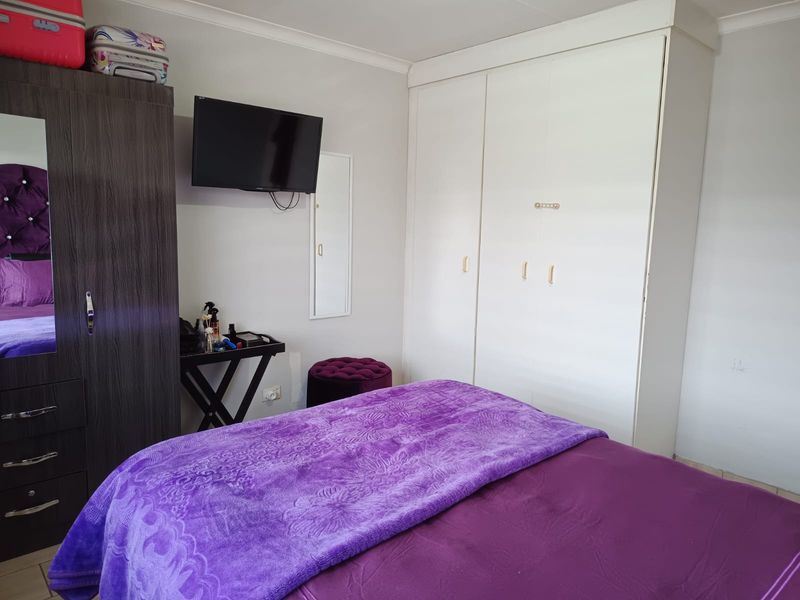 A bedroom featuring a built-in wardrobe with white doors and neutral wall finishes.