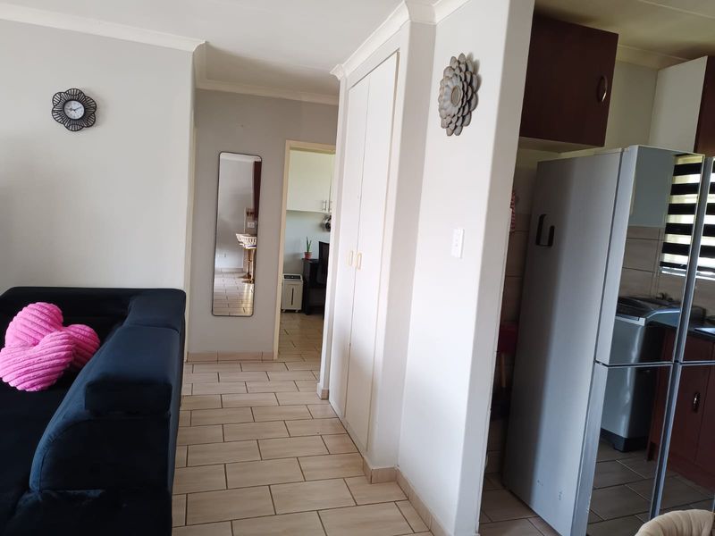 Open plan living area featuring tiled flooring and a built-in storage cupboard, providing a functional layout with access to the kitchen and adjacent rooms.