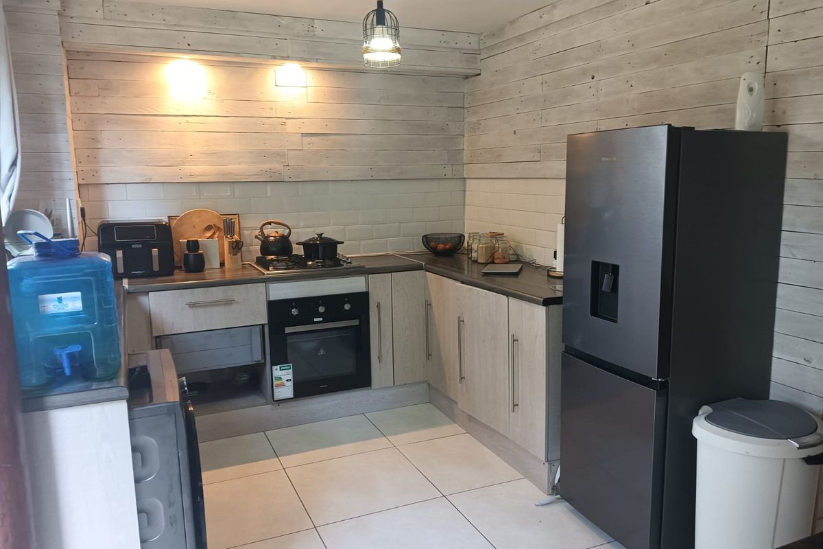 A functional kitchen featuring light-toned laminate cabinetry, subway tile backsplash, timber wall cladding, and built-in oven with gas hob.