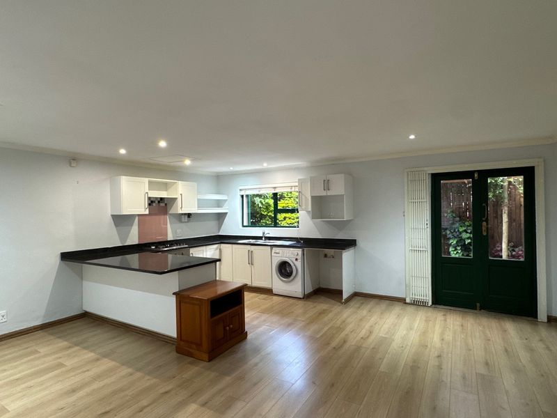 Spacious open-plan kitchen featuring modern laminate flooring, granite countertops, and direct access to the rear garden through double glass doors.