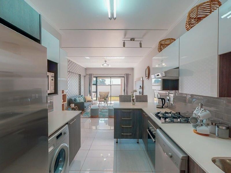 Modern open-plan kitchen and living area featuring sleek cabinetry, gas hob, tiled flooring, and direct access to the outdoor space through sliding doors.
