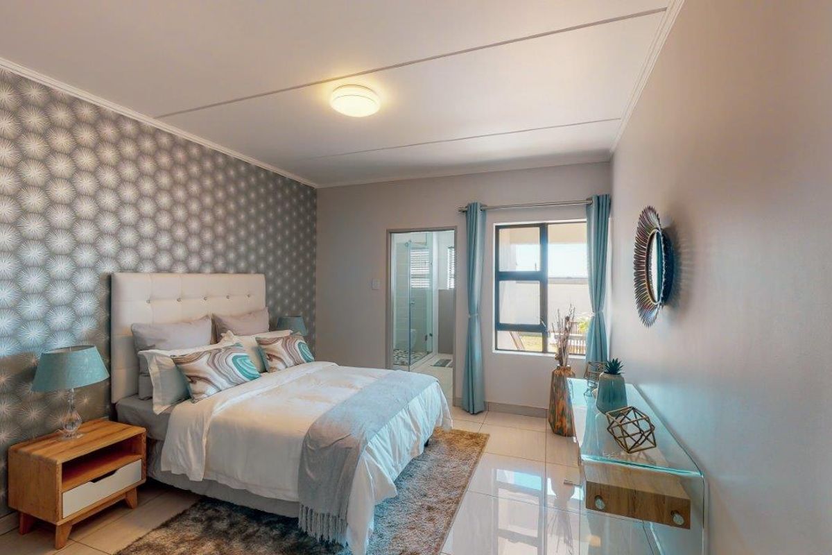 A well-maintained bedroom featuring tiled flooring, a decorative feature wall, and direct access to an en-suite bathroom.
