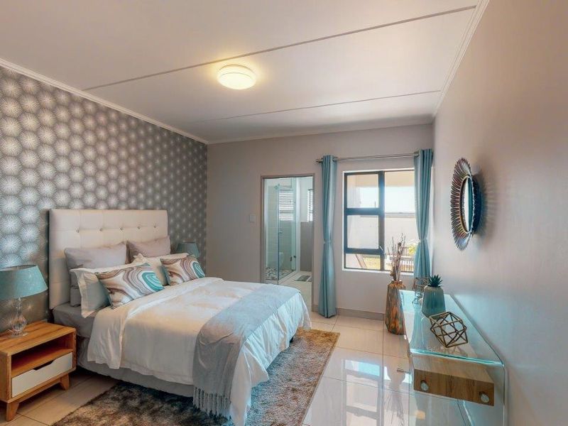 A well-maintained bedroom featuring tiled flooring, a decorative feature wall, and direct access to an en-suite bathroom.