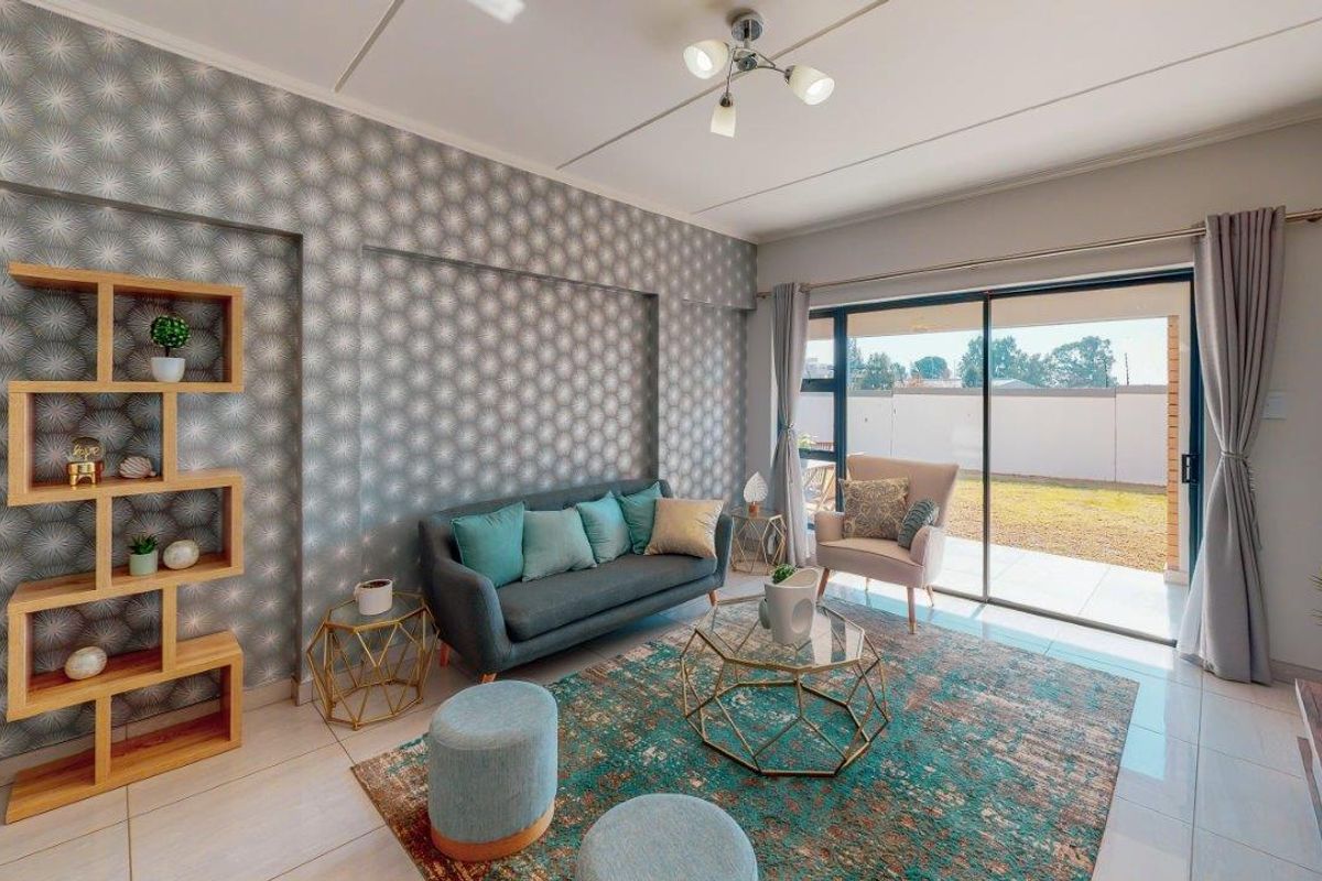 A bright living room featuring tiled floors, a feature wallpaper wall, and large sliding glass doors providing access to the outdoor area.