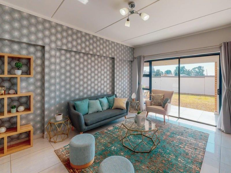 A bright living room featuring tiled floors, a feature wallpaper wall, and large sliding glass doors providing access to the outdoor area.