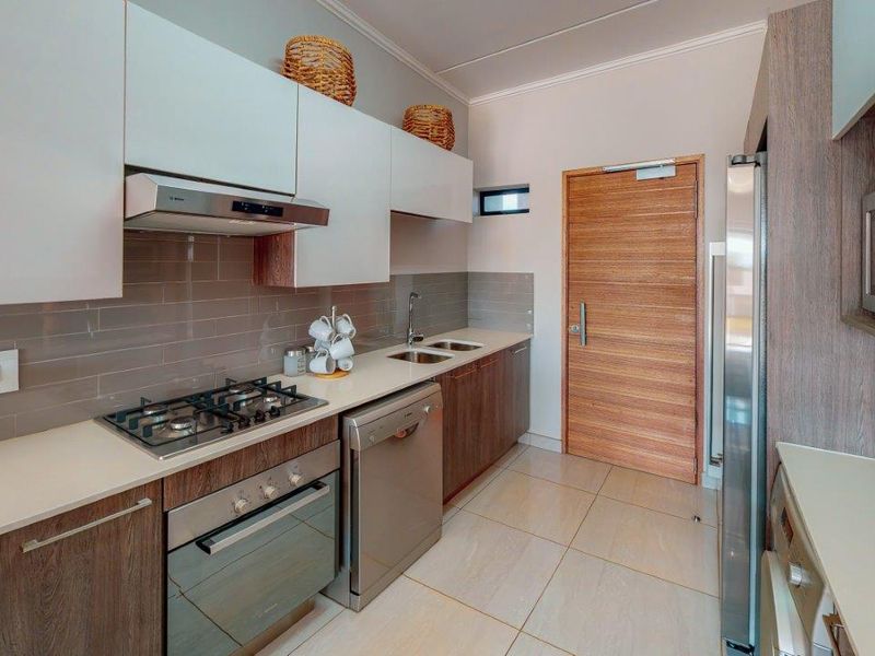 Modern kitchen featuring sleek laminate cabinetry, gas hob, built-in oven, extractor fan, integrated dishwasher, and tiled finishes.