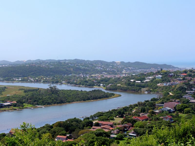 A scenic elevated view overlooking a river, lush coastal vegetation, and surrounding residential neighborhood.