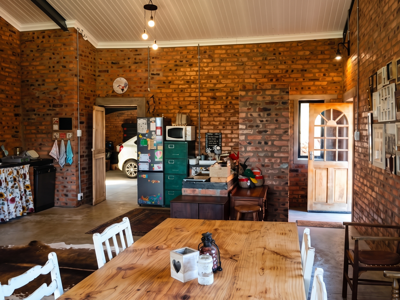 Spacious open-plan living and kitchen area featuring rustic exposed brick walls, high ceilings with exposed beams, and durable concrete flooring.