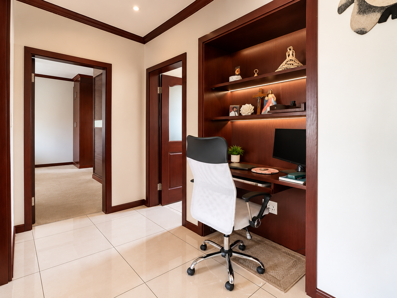 A functional home office nook featuring custom built-in wooden cabinetry, integrated shelving with LED lighting, and polished floor tiles.